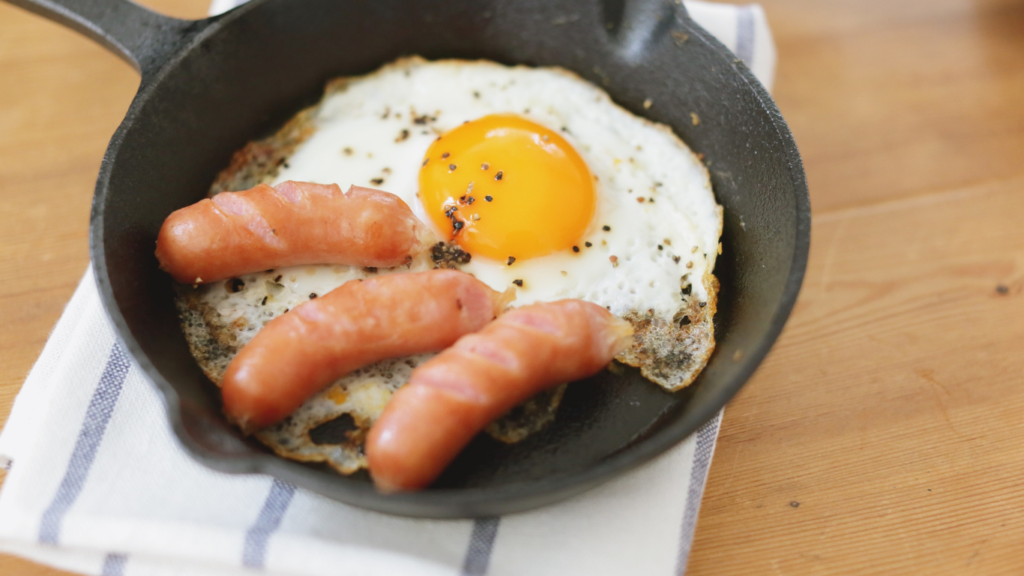 cast iron skillet cooking eggs and sausage